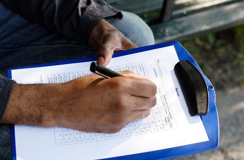 man holding blue clipboard filling out form
